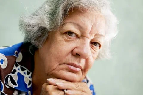 Portrait of serious old woman looking at camera with hands on chin Stock Photos