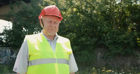 Portrait of serious senior engineer in uniform and helmet looks into the camera Video stock 135573405