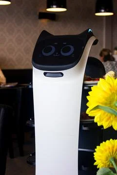 A portrait of a serving robot on wheels with a screen displaying a cute cat f Stock Photos