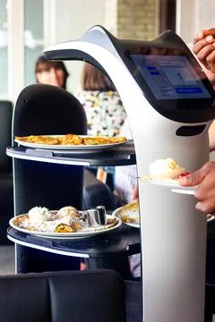 A portrait of a serving robot on wheels with a screen displaying a cute cat f Stock Photos