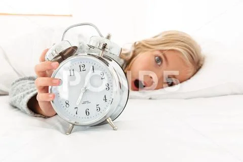 Portrait of a shocked cute little girl holding alarm clock Stock Photos