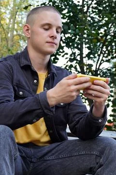 Portrait of a short-haired guy using a smart phone. a young adult, a student, an Stock Photos