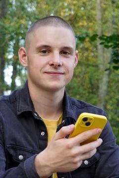 Portrait of a short-haired guy using a smart phone. a young adult, a student, an Foto stock
