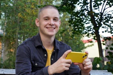 Portrait of a short-haired guy using a smart phone. a young adult, a student, an Stock Photos