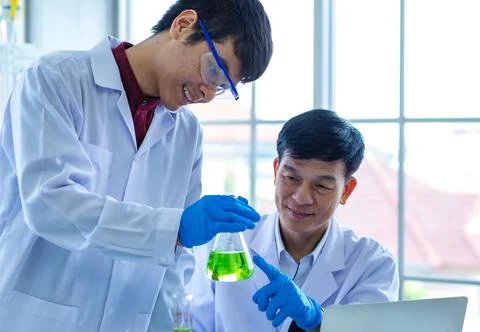 Portrait shot of Asian young male scientist in white lab coat safety goggle.. Stock Photos