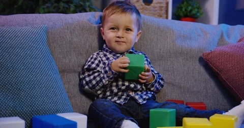 Portrait shot of the cute small funny boy playing with kid's cubes and wabing Stock Footage 82921015