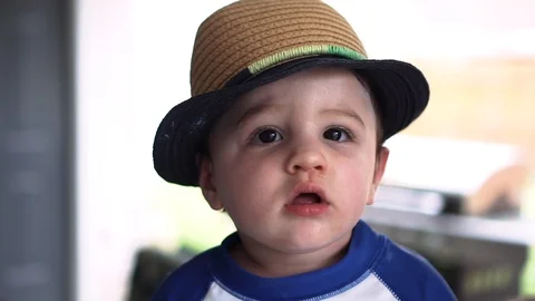 Portrait shot of an infant boy in a bathing shirt and straw hat by a pool. Stock Footage 104659002