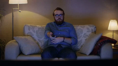 Portrait Shot of a Man Sitting on a Sofa in His Living Room, Watching TV Stock Footage 73293028