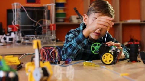 Portrait shot of nice blonde boy assembling a robot and smiling into the camera Stock Footage 82489794