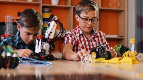 Portrait shot of two boys assembling and playing with robotic machines on the Stock Footage 82487953