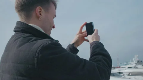 Portrait shot of the young guy taking photos of the yachts on the pier Stock Footage 151077281