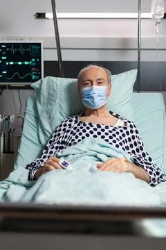 Portrait of sick senior man patient with chirurgical mask resting in hospital Stock Photos
