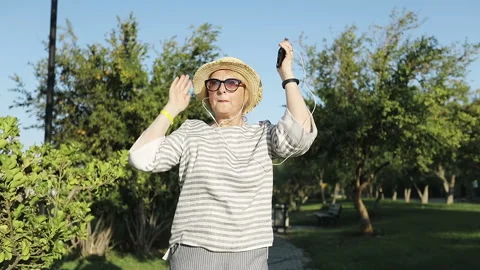 Portrait of sixty years old happy woman runs in headphones and sings. Stock Footage 128225577