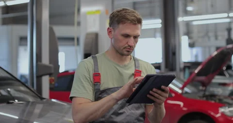Portrait of a skilled car mechanic in a workshop, with service Stock Footage 341869172
