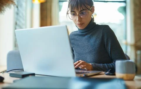 Portrait of skilled young female developer in eyeglasses concentrating on screen 스톡 사진