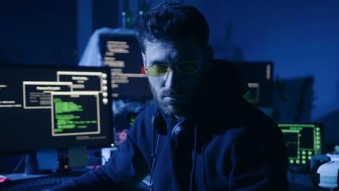 Portrait of skillful computer hacker sitting at desk with displays working in 스톡 사진