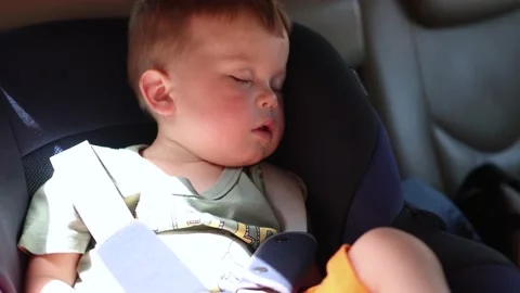 Portrait of sleeping little boy inside car in carseat in hot sunny day Stock Footage 155430904