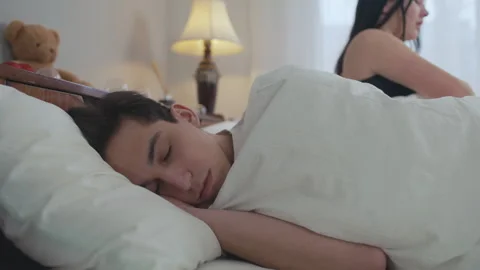 Portrait of sleeping young man lying in soft comfortable bed as woman waking up Stock-Footage 240719739