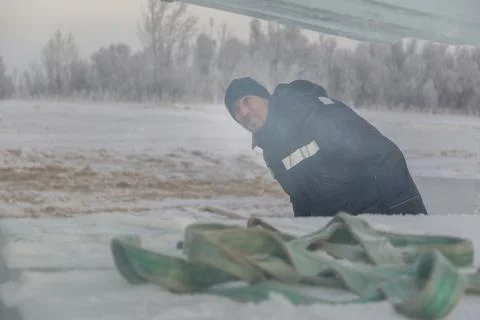 Portrait of a slinger in a blue jacket unloading ice blocks Fotos Stock