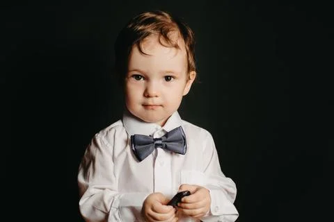Portrait of a small boy on a dark background in a white shirt and bow tie Stock Photos