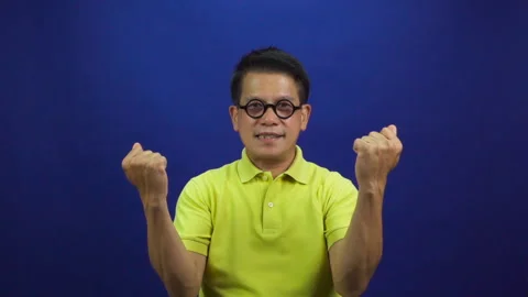 Portrait of smart middle-aged asian man in casual yellow T shirt feeling excited Stock Footage 219190083