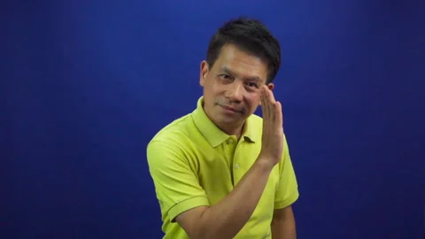 Portrait of smart middle-aged asian man in yellow T shirt whispering something Stock Footage 219190086