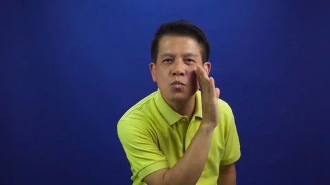 Portrait of smart middle-aged asian man in yellow T shirt kissing something Stock Footage 219190089