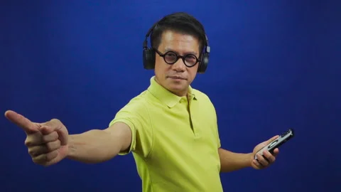 Portrait of smart middle-aged asian man in yellow T shirt listening music Stock Footage 219190094