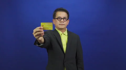 Portrait of smart middle-aged asian businessman wearing suit showing credit card Видео 219190129