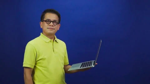 Portrait of smart middle-aged asian man in casual yellow T shirt holding laptop Stock Footage 219469053
