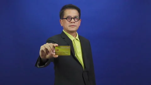 Portrait of smart middle-aged asian businessman wearing suit showing credit card 스톡 동영상 219469090
