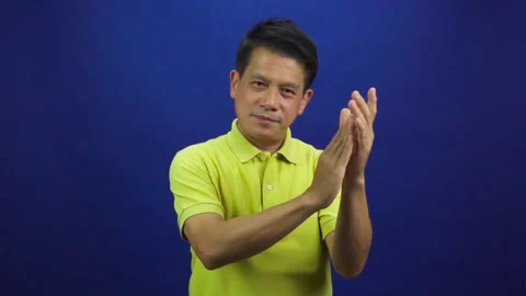 Portrait of smart middle-aged asian man in yellow T shirt applauding to camera Stock Footage 219469109