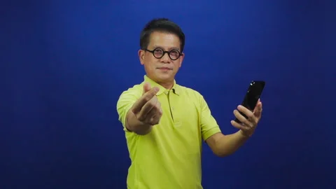 Portrait of smart middle-aged asian man holding smartphone and giving mini heart Stock Footage 219469256
