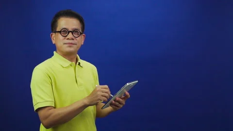 Portrait of smart middle-aged asian man in yellow T shirt holding digital tablet Stock-Footage 219469271