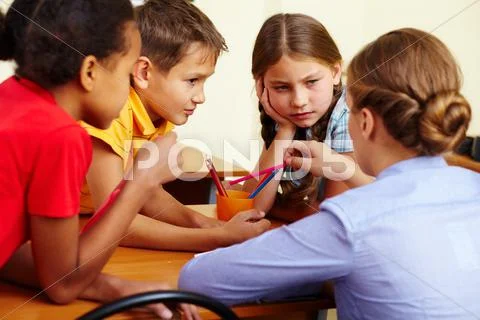 Portrait of smart schoolchildren and their teacher interacting in classroom Stock Photos