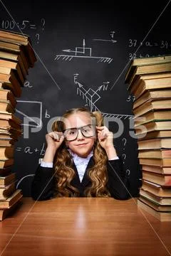 Portrait of a smart schoolgirl in glasses posing with books over school black Stock Photos