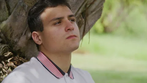 Portrait of a smart, young guy enjoying sunny morning and lush greenery in the Stock Footage 235772761