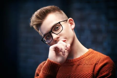 Portrait of a smart young guy in a pullover and glasses. Studio shot. Men's b Stock Photos