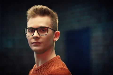 Portrait of a smart young guy in a pullover and glasses. Studio shot. Men's b Stock Photos