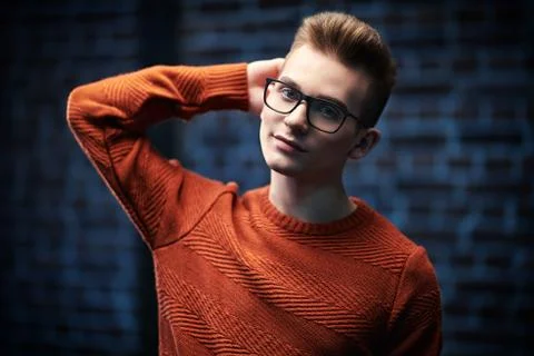 Portrait of a smart young guy in a pullover and glasses. Studio shot. Men's b Stock Photos