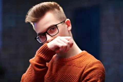 Portrait of a smart young guy in a pullover and glasses. Studio shot. Men's b Stock Photos