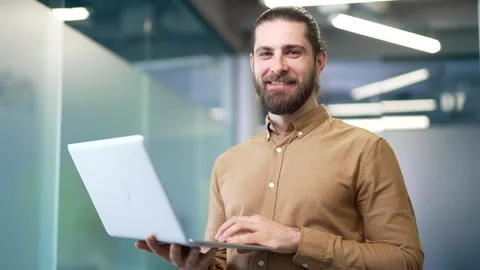Portrait of a smiling admin IT engineer works on a laptop computer standing  Stock Footage 308813267