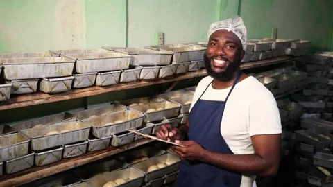 Portrait of smiling African baker holding clipboard in bakery, proud SME Stock Footage 346565291