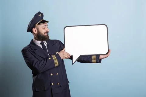 Portrait of smiling airline pilot points to blank speech bubble sign Stock Photos