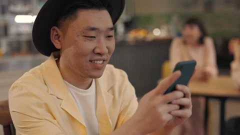 Portrait of smiling asian guy using smartphone at cafe Video stock 168317887