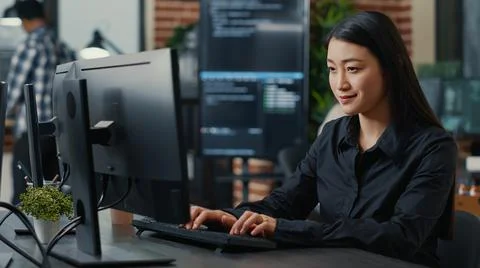 Portrait of smiling asian programer focused on writing code sitting at desk Stockfoto's