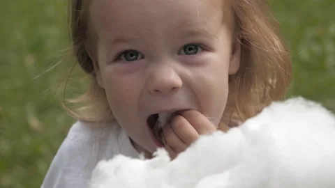 Portrait of smiling baby eats cotton candy and looking at the camera 库存影片 99487906