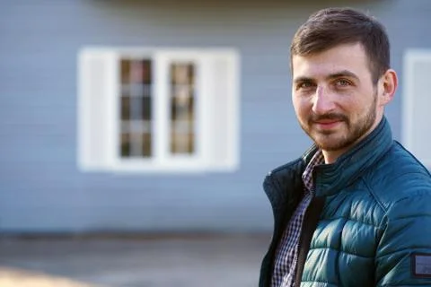 Portrait of a smiling bearded man on the background of a blue house in the sun. Stock Photos
