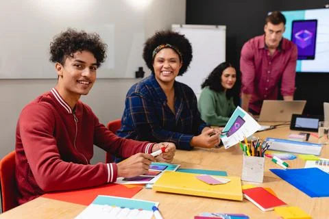 Portrait of smiling biracial app developers with documents in board room Stock Photos