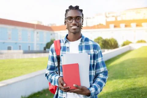 Portrait of smiling black guy with backpack and workbooks outdoors Stock Photos